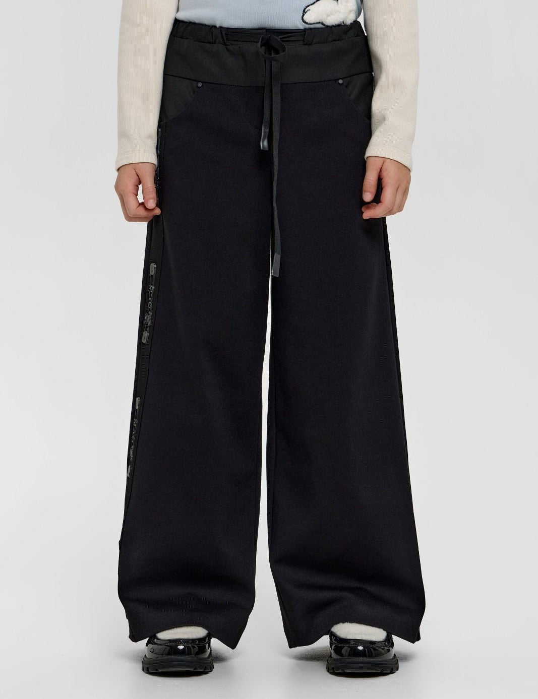 Child modelling black wide-leg trousers with side detailing