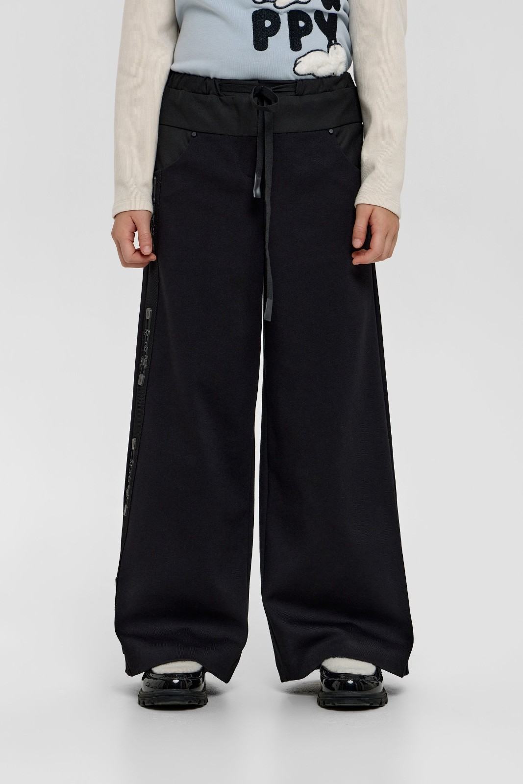 Child modelling black wide-leg trousers with side detailing